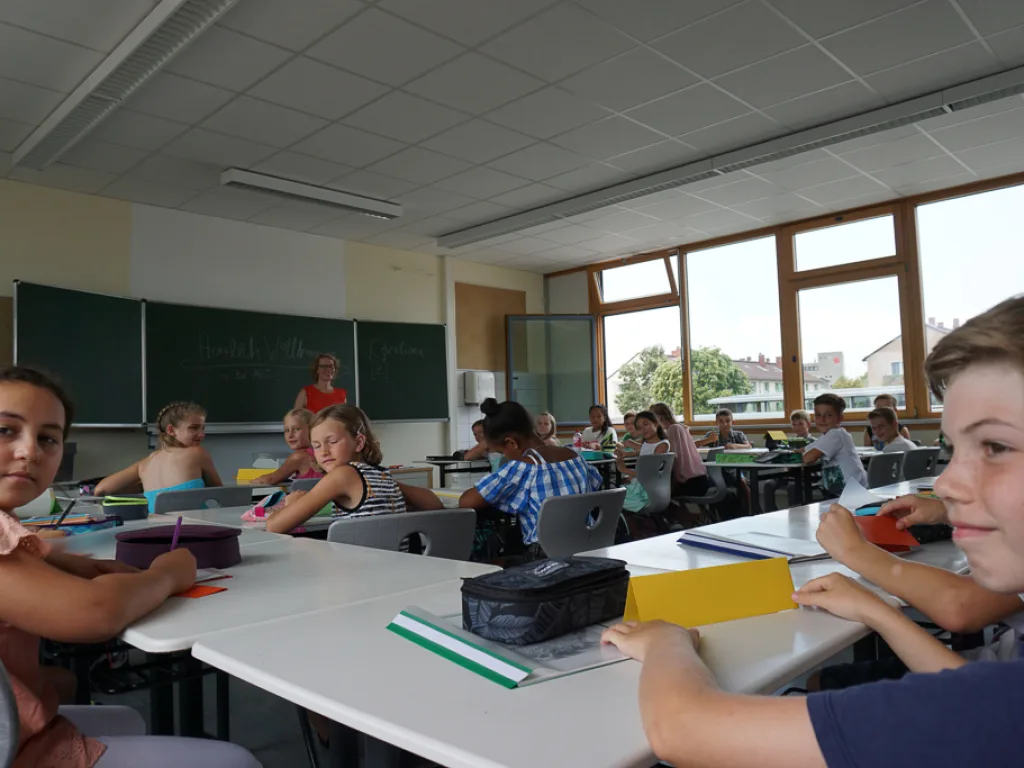 Kinder arbeiten an Gruppentischen im Unterricht.